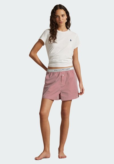 Vitt kortärmat t-shirt med en liten logo, i kombination med röda och vita randiga shorts med resårmidja och knäppning.