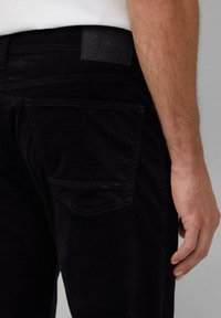 Czarne dżinsy kordurowe z tylną kieszeni�ą. Charakteryzują się gładką fakturą, subtelnymi prążkami oraz prostą czarną łatą w pasie.