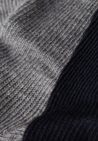Dzianina w kolorze szarym i ciemnym granacie, o gładkiej fakturze z drobnym prążkowanym wzorem oraz kontrastującymi tkanymi sekcjami.
