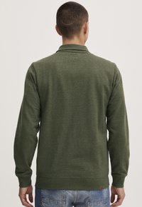 Oliven grønn genser med lange ermer, ribbestrikkede mansjetter og nederkant, laget av et mykt stoff, med et enkelt design uten mønstre eller pynt.