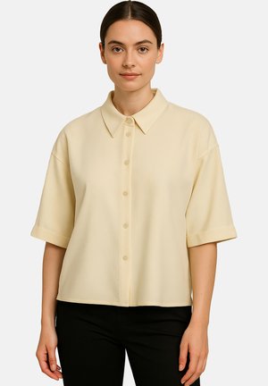 Short-sleeve, collared shirt in soft yellow fabric with a textured finish, featuring a button front and rolled cuffs.