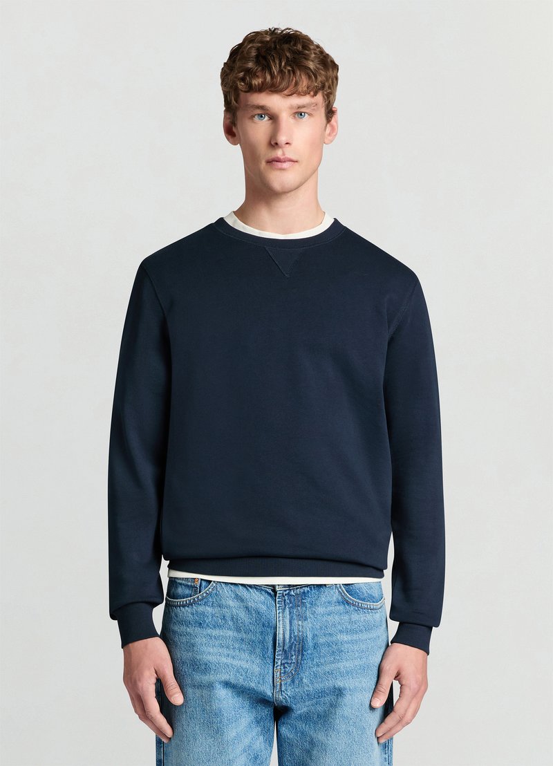Sweat-shirt bleu marine à col rond avec poignets et ourlet côtelés, doté d'un col intérieur blanc contrastant. Mélange de coton, coupe décontractée, design minimaliste.