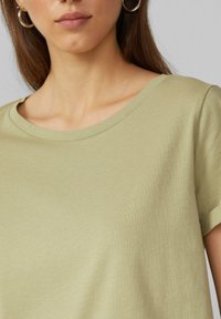 Lichtgroen katoenen T-shirt met een ronde hals en korte mouwen. De stof lijkt glad en heeft een subtiele textuur.