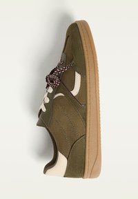 Baskets vert kaki avec une tige en daim texturé, des accents crème et une semelle en caoutchouc. Présente des lacets sombres contrastants et des détails brodés.