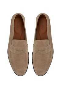 Mocassini in suede beige con suola piatta, texture liscia, dettagli cuciti e un accento decorativo sulla tomaia. Logo del marchio sulla soletta.