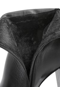 Bottine en cuir noir avec fermeture éclair, dotée d'une douce doublure en fourrure et d'une texture lisse. Le talon est épais et robuste.