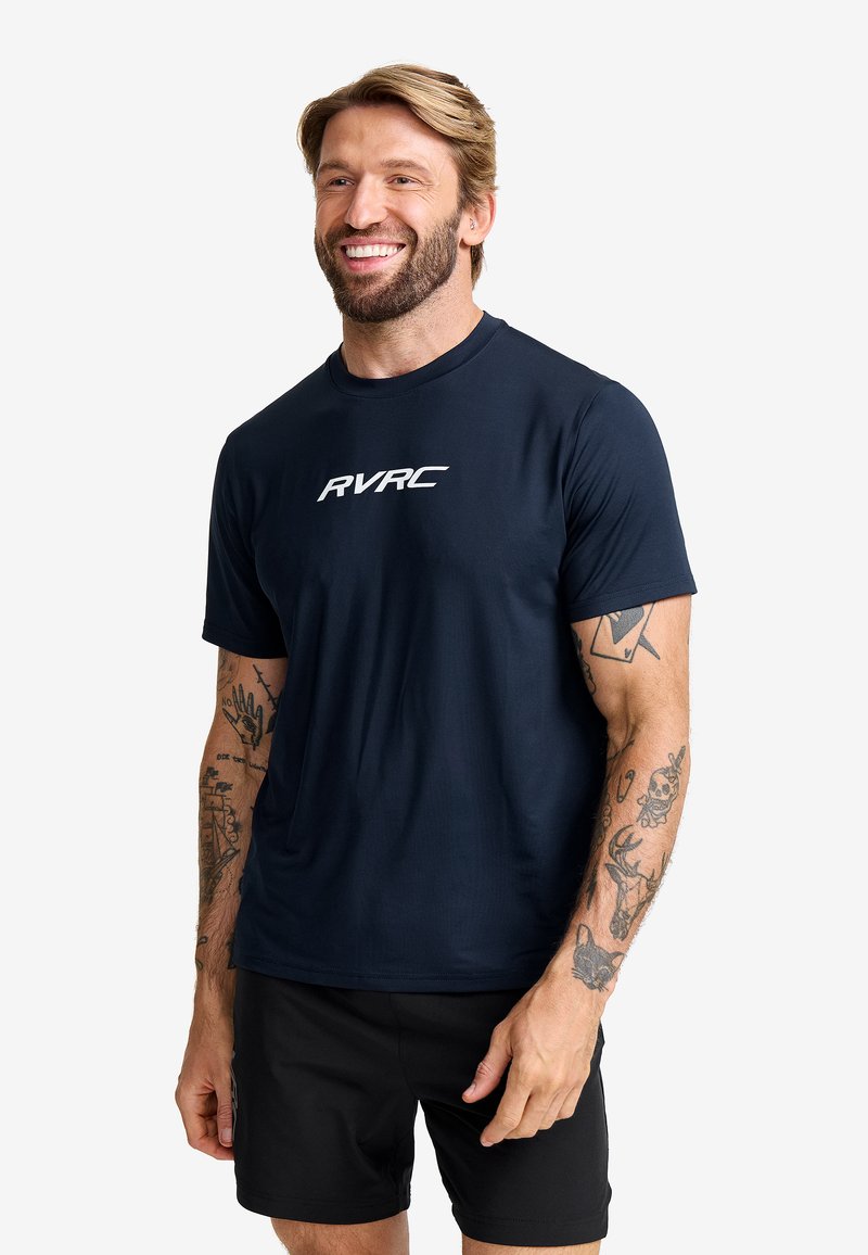 Mörkblå atletisk tröja i mjukt tyg med en vit "RVRC"-logotyp på bröstet. Kortärmad och med rund halsringning.