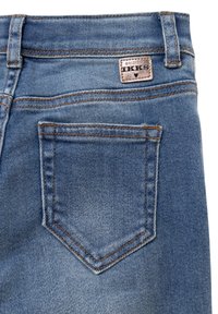 Jeans in denim blu sbiadito con una piccola tasca posteriore, cucita con filo marrone a contrasto. Presenta un'etichetta in pelle con il marchio "IKKS".