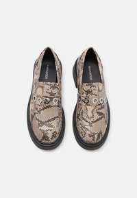 Mocassini con motivo in pelle di serpente in beige e marrone, con suola in gomma nera e dettagli in hardware argentato su una fascia decorativa.