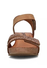Sandalo in pelle tan con due fasce larghe. Presenta una fascia accentuata testurizzata e luccicante e una suola naturale simile al sughero.