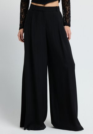 Sorte breddebenede bukser med høj talje, der har striber og en glat tekstur. Stoffet hænger elegant, og er parret med et enkelt bælte.