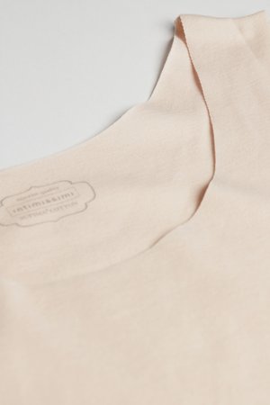 Zachte beige sokken gemaakt van premium katoen, plat uitgestald om de gladde stoftextuur en het subtiele merkembleem aan de binnenkant te tonen.