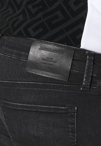 Schwarze Denim-Jeans mit einer eleganten Textur. Ausgestattet mit einem hinteren Lederpatch, der mit "JACK & JONES" geprägt ist, und dezenten Nähten.