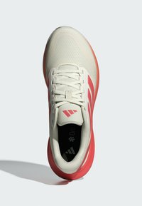 Jasnobeżowe buty sportowe z różowymi akcentami, siateczkowa cholewka, płaskie sznurowadła, amortyzowana podeszwa oraz logo na języku i podeszwie.