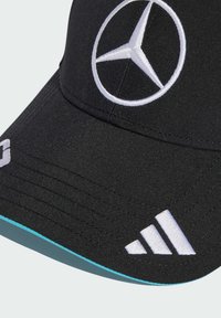 Sort kasket med hvidt broderet Mercedes-logo og Adidass tre striber. Har en struktureret overflade og en turkise kant på sk brim.