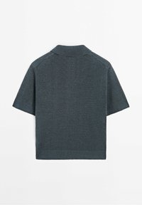 Polo a maniche corte in tessuto di maglia verde scuro. Presenta un colletto, polsini a coste e una texture liscia con dettagli minimi.