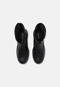 Botas de tobillo de cuero negro con un acabado suave, paneles laterales elásticos y un diseño de punta redondeada, que cuentan con una plantilla acolchada.