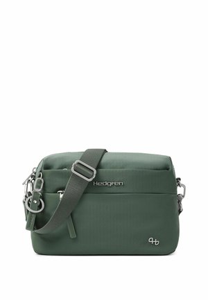 Grüne Crossbody-Tasche mit verstellbarem Riemen, Frontreißverschlusstasche, Metalllogo "Hedgren," und Schlüsselanhängerbefestigung auf der linken Seite.