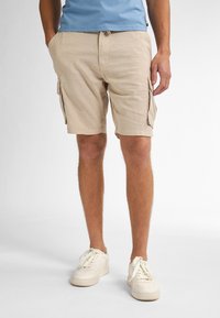Beige cargoshorts met twee zijzakken en een tailleband met koord. Gecombineerd met witte sneakers. De textuur lijkt licht en casual.
