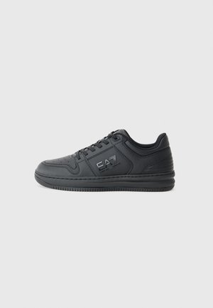 Zwarte sneaker met een gladde leren afwerking, geperforeerde details op de neus en een strak ontwerp. Bevat een logo aan de zijkant en een gestructureerde zool.