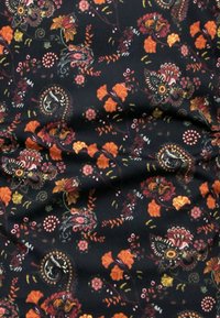 Zwarte stof met een bloemenpatroon in oranje, rood en gele tinten, met ingewikkelde ontwerpen van bloemen en paisley-vormen.