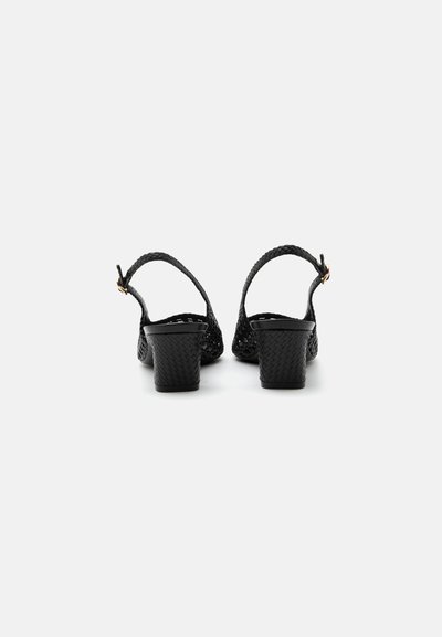 Escarpins slingback tissés noirs avec talons blocs et petite boucle dorée sur les brides, vus de derrière sur fond blanc.