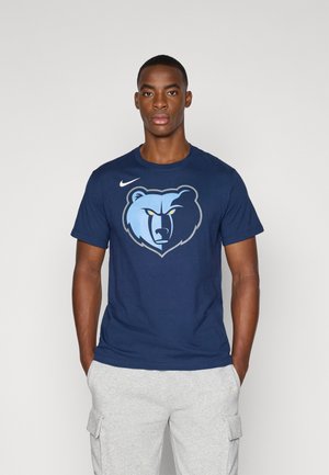 Tamno plava pamučna majica s grafikom svijetloplavog medvjeda sa žutim očima. Uključuje Nike logo na lijevoj ramenu.