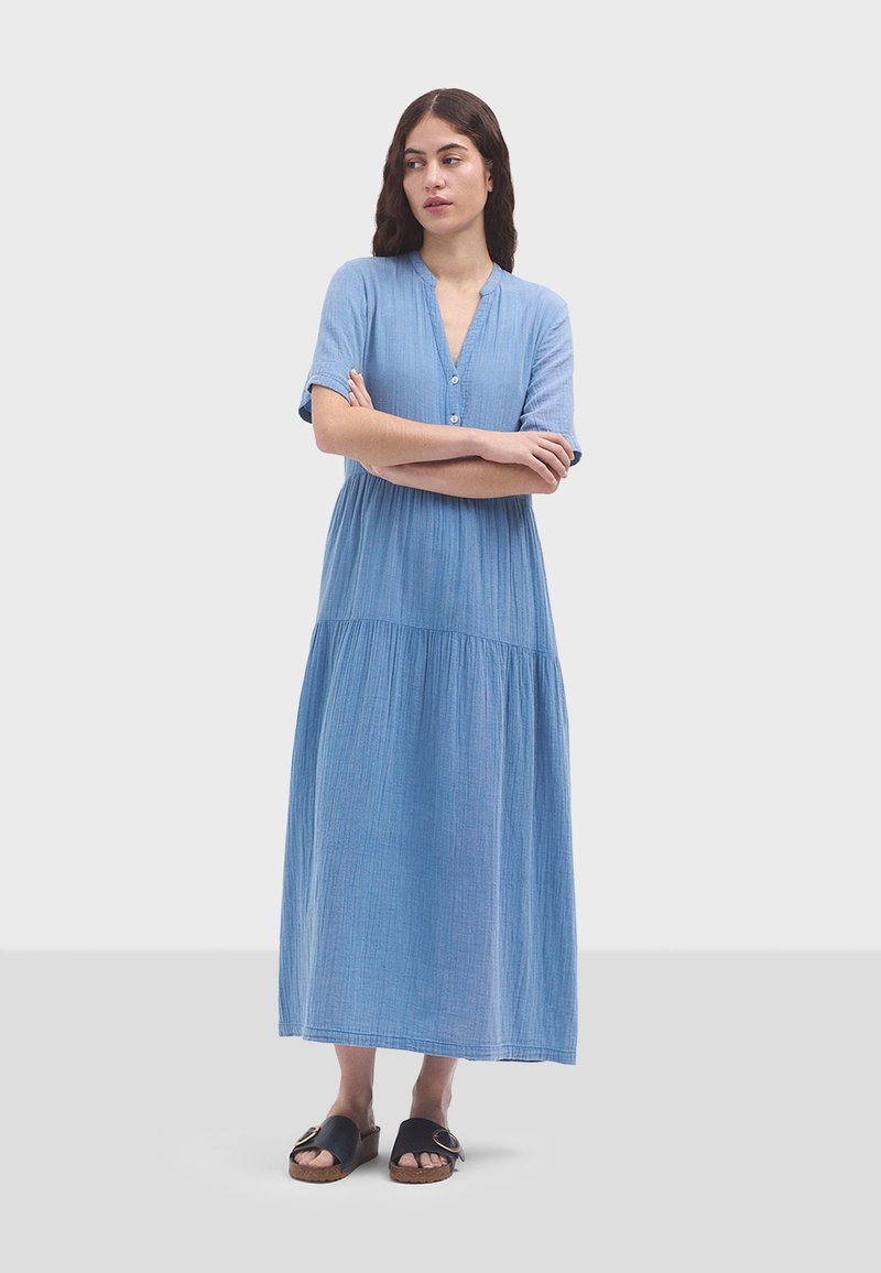 Himmelblaues, knielanges Kleid aus weichem Stoff. Verfügt über kurze Ärmel, eine Knopfleiste und einen fließenden, gerafften unteren Teil.