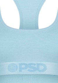 Šviesiai mėlynas sportinis liemenukas su lenkta nugaros dizainu, turintis tekstūruotą juosmenį ir subtilų ženklinimą toje pačioje spalvoje. Lygi, elastinė medžiaga.