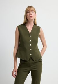 Bezrękawnik w oliwkowo-zielonym kolorze z dekoltem w serek, z sześcioma perłowymi guzikami i dwoma przednimi kieszeniami; konstrukcja o kroju dopasowanym.