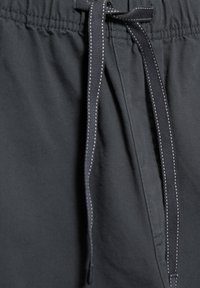 Sorte shorts med elastisk taljebånd, der har en frontsnor med kontrastfuld hvid syning og en glat stoftekstur.