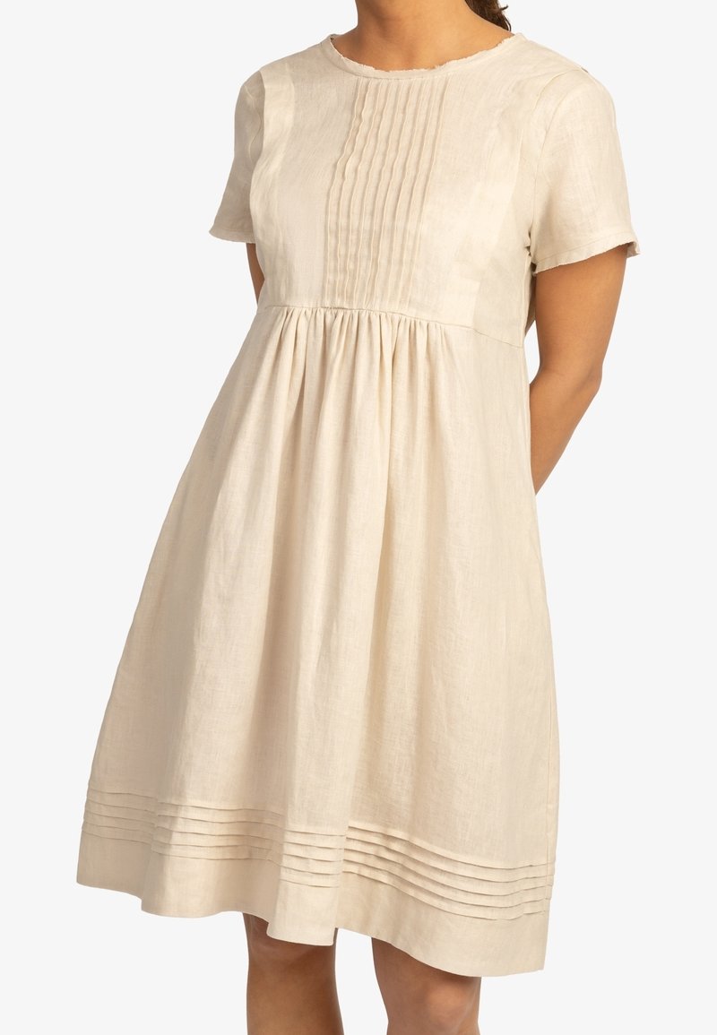 Dámské šaty s krátkým rukávem z lehkého lnu ve světle béžové barvě s plisovaným vrškem a nařasenou sukní. Obsahuje horizontální švy blízko lemu.