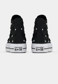 Δερμάτινα ψηλά μαύρα Converse sneakers με μεταλλικά στρας, υφασμάτινη υφή και λευκές καουτσούκ σόλες, που διαθέτουν λογότυπο στη φτέρνα και επίπεδη σχεδίαση κορδονιών.