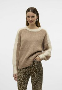 Pull en tricot beige avec des manches en crème, doté d'un col rond. Assorti avec un pantalon moulant imprimé léopard.