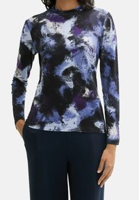 Halenka s dlouhým rukávem z měkké tkaniny s černým, fialovým a modrým abstraktním vzorem. Vyšší límec, přiléhavý střih a bezšvové manžety.