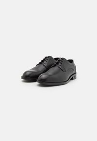 Pantofi de piele negri, cu vârful rotunjit, design cu șireturi și suprafață texturată. Au toc mic și detalii subtile ale mărcii pe lateral.