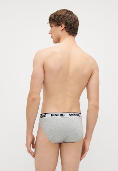 Hallid puuvillased aluspesu musta logo vööga, millel on tihe istuvus ja sile tekstuur. Vaade tagant neutraalses taustas.