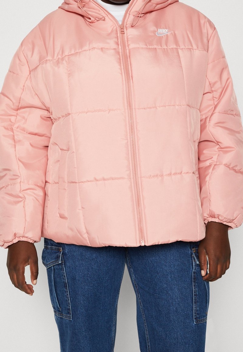 Rosa puffjacka med dragkedja fram, elastiska ärmslut och huva. Har en puffy quiltad design och en liten vit logga på bröstet.