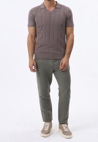 Korte mouwen gebreide polo in mauve met een V-hals, voorzien van een textuurpatroon en geribbelde accenten, gecombineerd met lichtgroene op maat gemaakte broeken en beige sneakers.