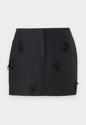 Svart skjørt med en tettsittende design og teksturerte, frynsete detaljer spredd over stoffet. Glatt materiale uten synlige festemidler.