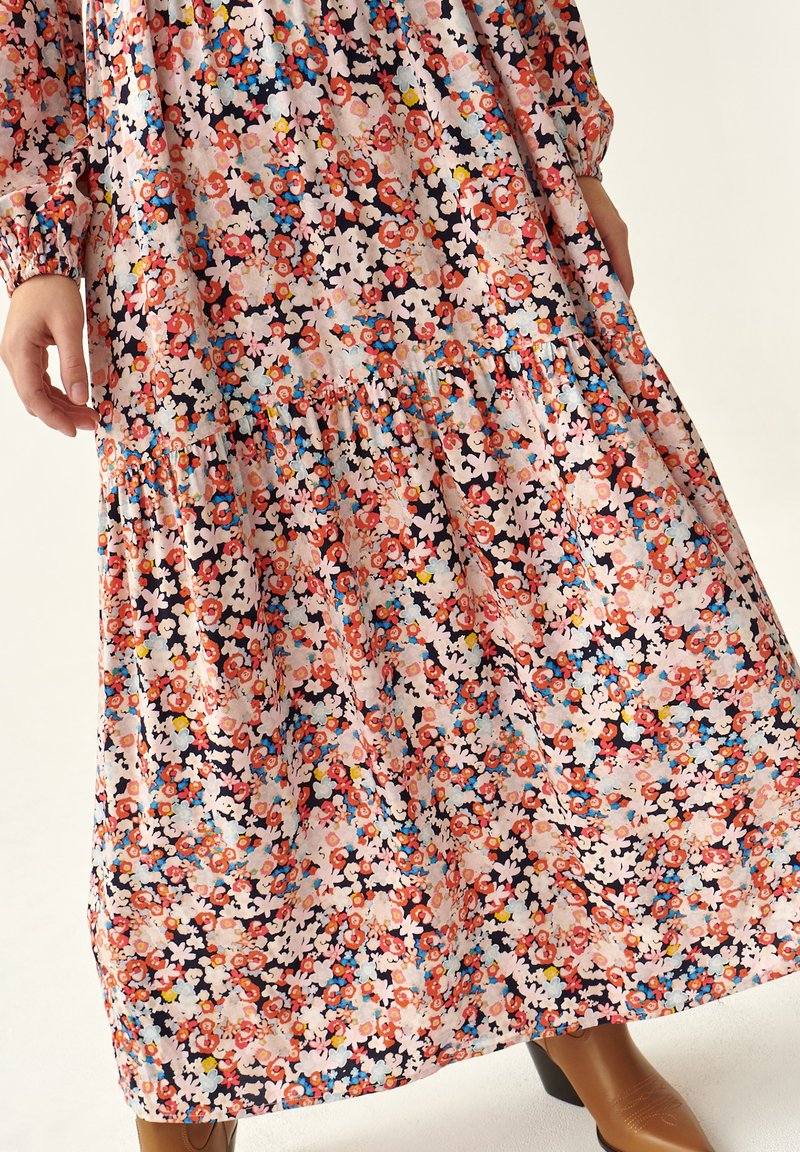 Maxikleid mit floralem Muster, das einen rosa Hintergrund mit mehrfarbigen Blumen zeigt. Es hat geraffte Lagen, lange Ärmel und eine lockere Silhouette.