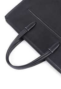 Sort læder tote taske med struktureret overflade, udstyret med to buede håndtag og en lynlåslukning i toppen. Minimalistisk design uden synlige logoer.