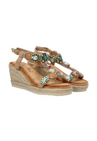 Sandalias de cuña beige con suela de esparto texturizada. Presenta una variedad de piedras de colores y cuentas dispuestas en un patrón decorativo.