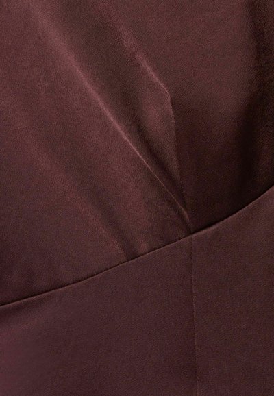 Tejido burdeos con una textura suave, con pliegues diagonales y una costura, creando un diseño estructurado.