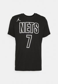 Černé bavlněné tričko s bílým nápisem "NETS" a číslem "7", s logem Jumpman na horní levé straně. Krátké rukávy a kulatý výstřih.