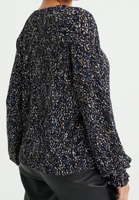 Pull en maille texturée bleu marine avec des éclats multicolores, doté de manches longues et d'une coupe ample. Poignets et col côtelés pour un détail supplémentaire.
