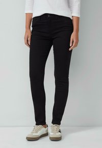 Zwarte skinny jeans van denim met een gladde textuur, voorzien van voorzakken en een knoopsluiting. Draag ze met witte en beige sneakers.