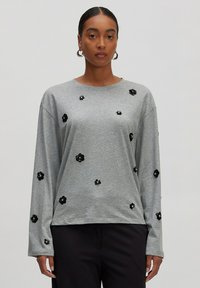 Grijze lange mouwen shirt met zwarte bloem applicaties van pailletten, ronde halslijn en een ontspannen pasvorm. Zachte stof met een gladde textuur.