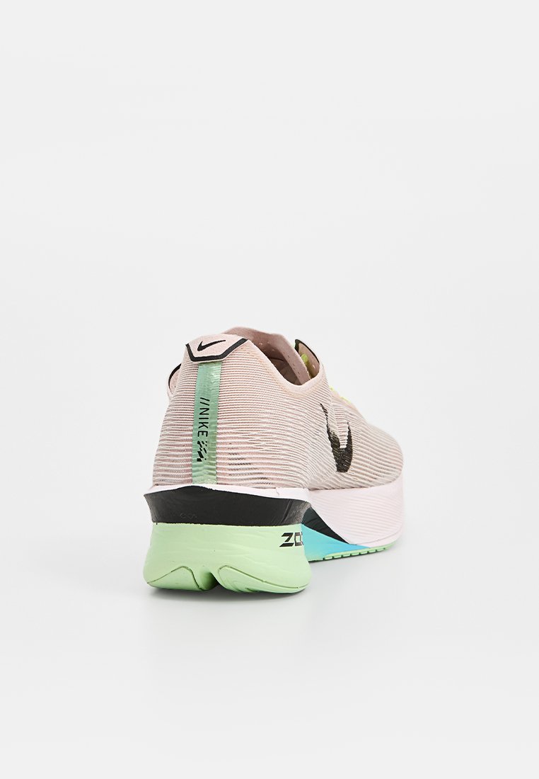 Zapatilla de running Nike con parte superior texturizada en rosa claro, logo swoosh en negro, lengüeta en el talón verde y suela multicolor para estabilidad y agarre.