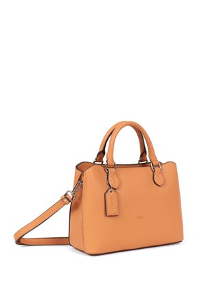 Sac à main en cuir fauve avec double poignée, bandoulière amovible et une étiquette de marque suspendue à une des poignées.